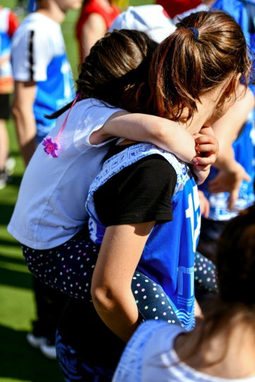 two young girls hugging each other on a field