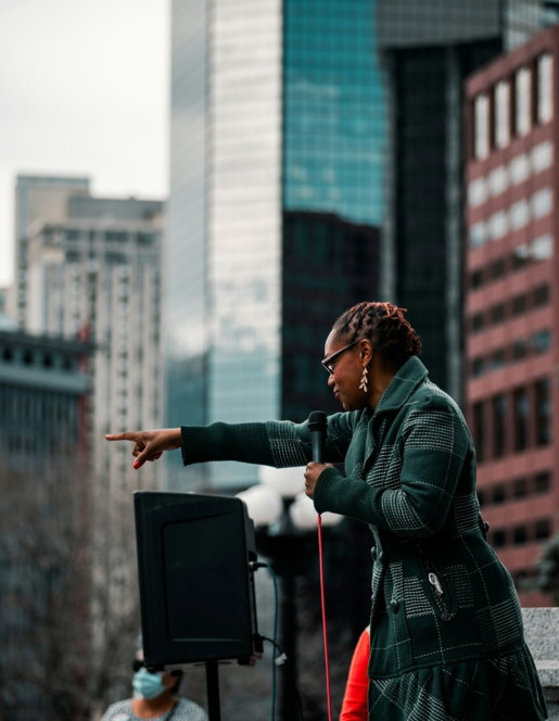 woman in green jacket standing near building during daytime